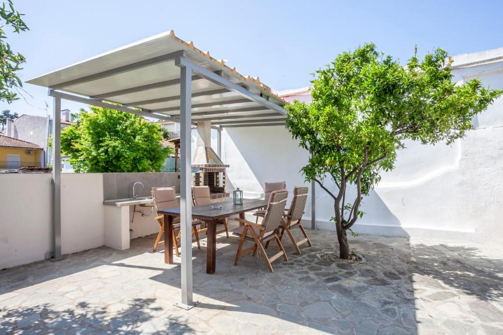 a wooden table and chairs under a pergola at Old Square House in Pefkochori