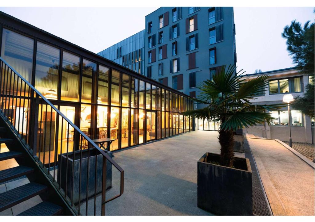 un bâtiment avec un palmier devant dans l'établissement Résidence Nemea Montecristo, à Nantes