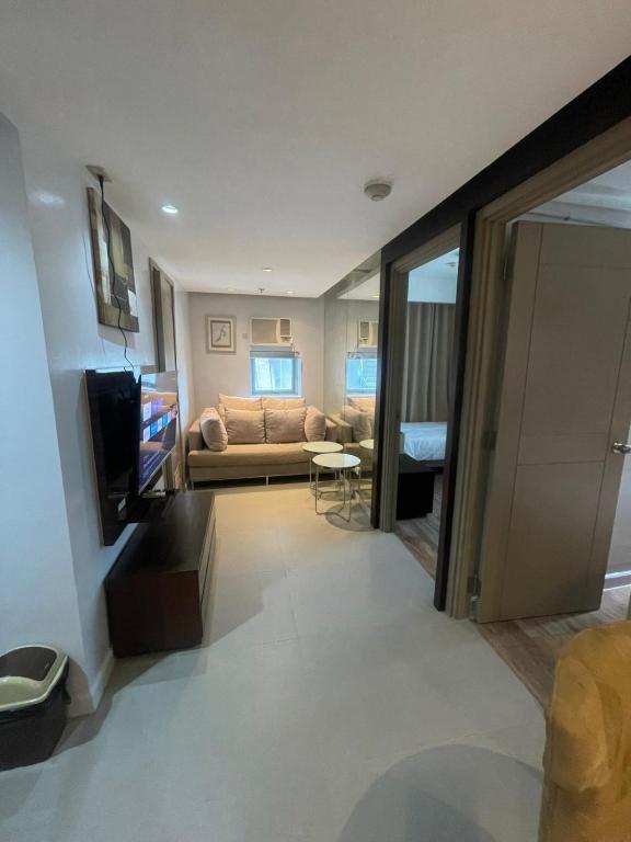 a living room with a couch and a television at Makati City Serenity Tower 2501 in Manila