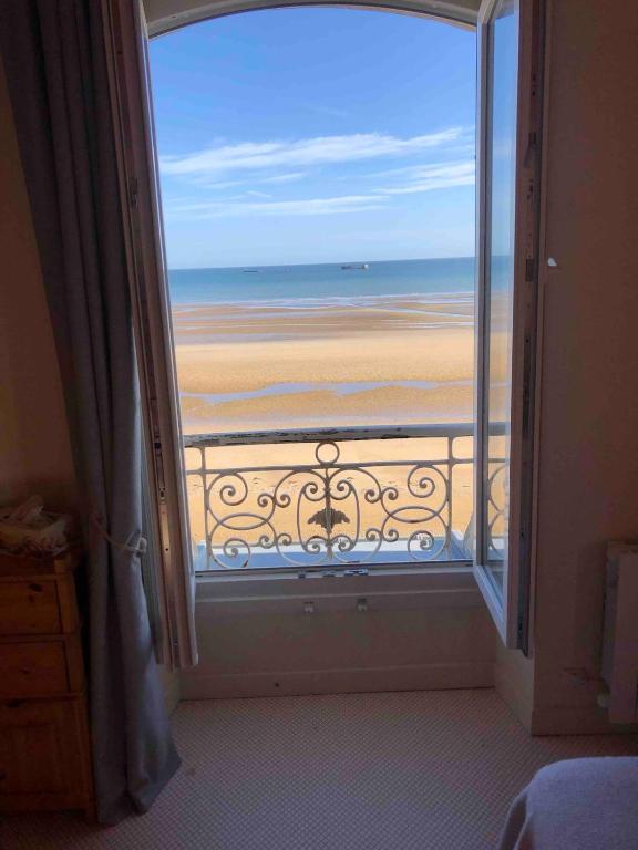 Cette chambre offre une vue sur la plage depuis sa fenêtre. dans l'établissement L'Horizon Bleu, front de mer, jardin, parking, wifi, à Asnelles