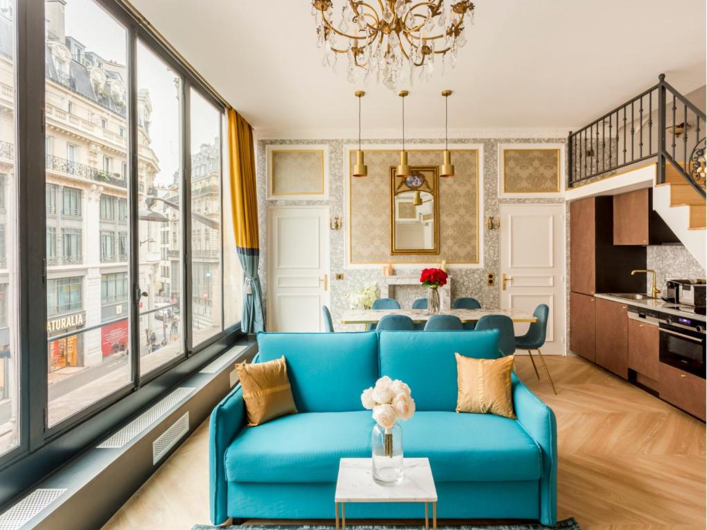 - un salon avec un canapé bleu et de grandes fenêtres dans l'établissement Merveil - Luxury Suite - Louvre - Reaumur II, à Paris