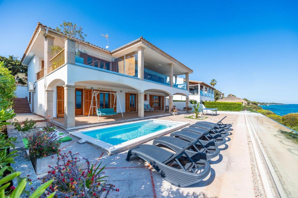 a house with a swimming pool and lounge chairs at Villa Can Torrens de Alcudia in Alcudia