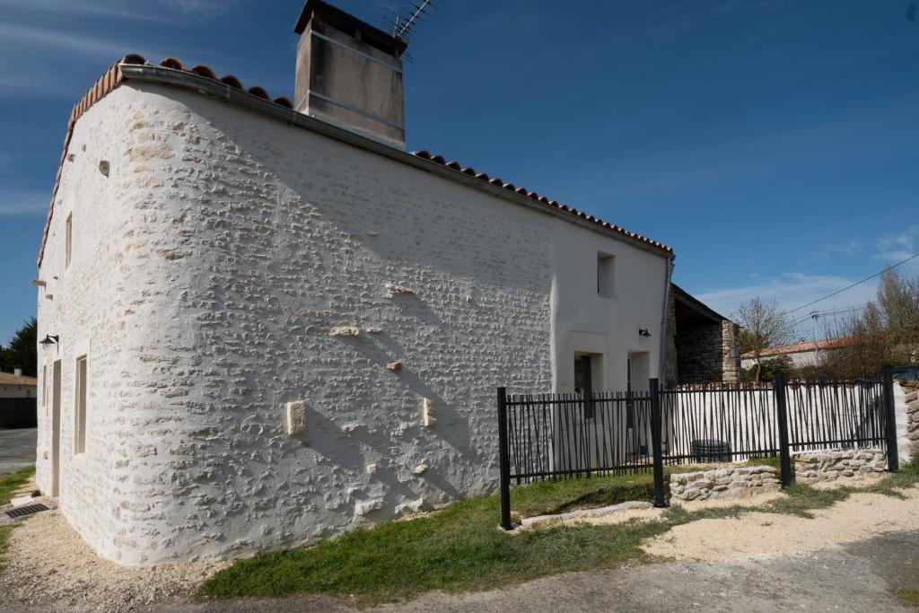 un edificio in mattoni bianchi con una recinzione nera di Le Clos du Tramaillou gite La Grand Voile pour 6 S a Annezay