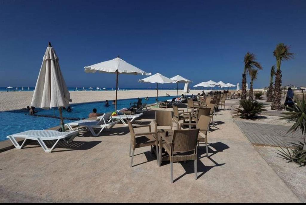 eine Gruppe von Stühlen und Sonnenschirmen am Strand in der Unterkunft Chalet in Dawwār Abū Duray‘ah ‘Abd al Karīm