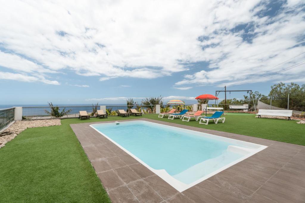 a swimming pool in a yard with chairs and tables at La Atalaya in Adeje