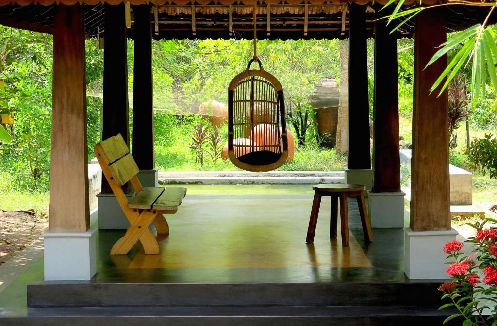 a porch with a chair and a bird cage at Clayfingers Art Cottage in Trichūr
