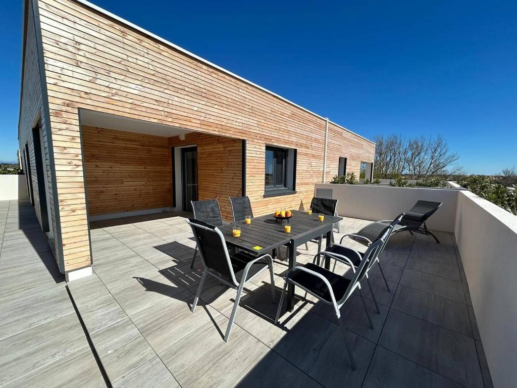 un patio avec une table et des chaises sur une terrasse dans l'établissement NAÏA ALO, à Sérignan