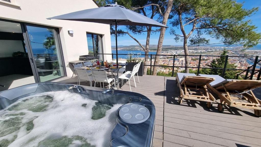 - un bain à remous sur une terrasse avec une table et un parasol dans l'établissement VILLA ROUQUIER, Vue Panoramique, Mer et Port de Sète, Climatisé, Jacuzzi, à Sète