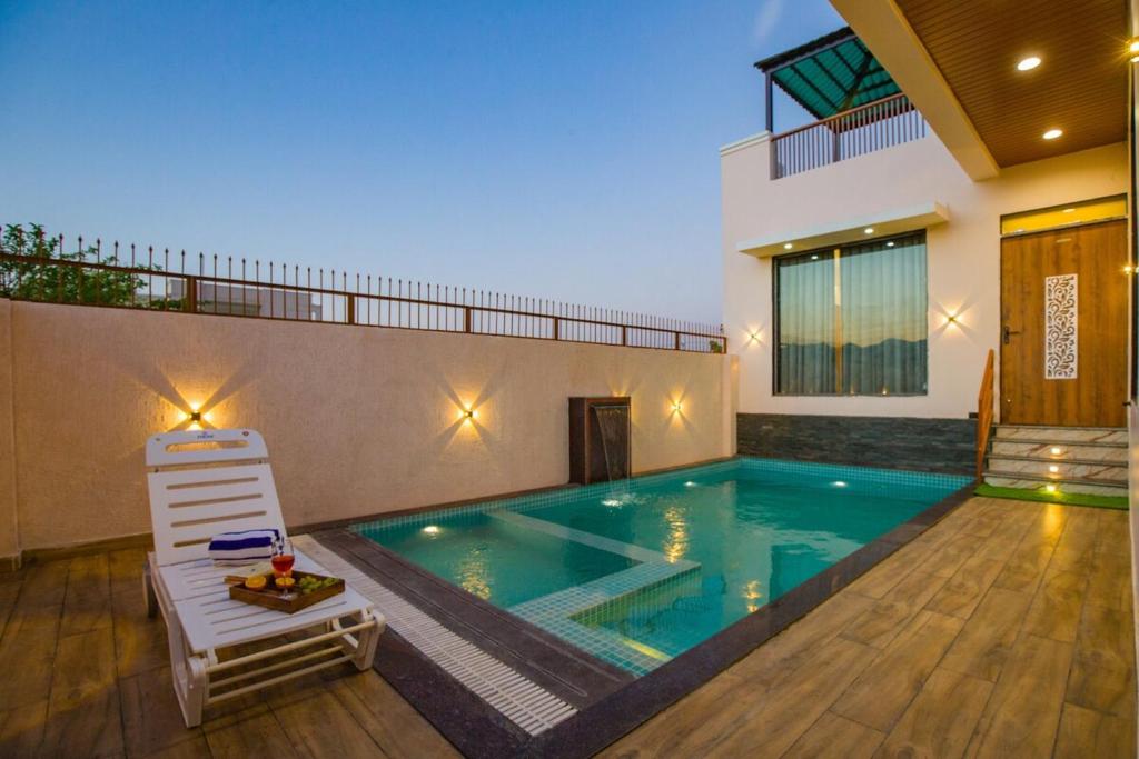 a swimming pool with a chair in a house at Alaya Stays Parvam Retreat 2-BHK Villa With Private Pool, Garden, Terrace & Aravali Hill Views in Thūr