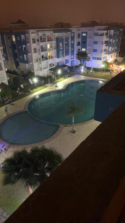 a large swimming pool in front of a building at night at Residence avec piscine in Martil
