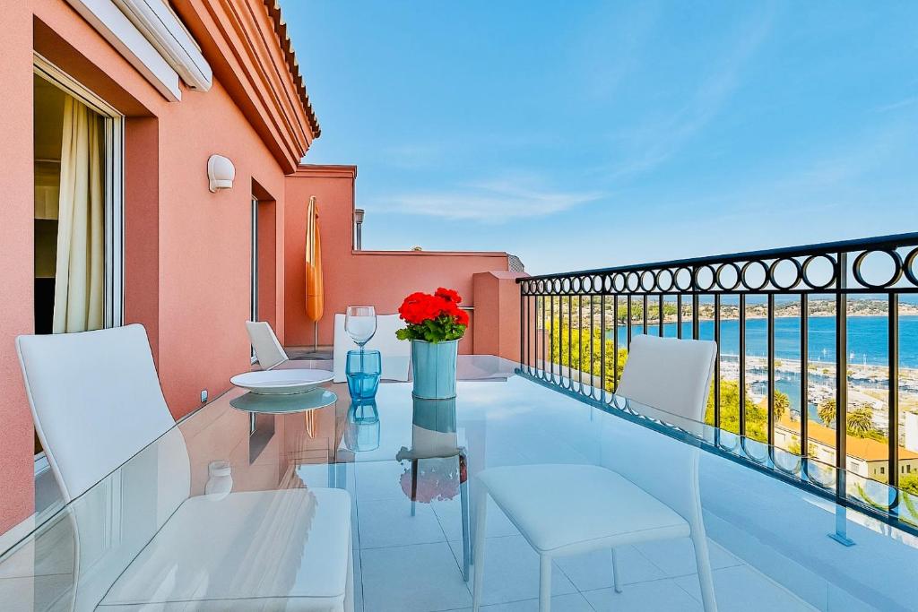 d'un balcon avec une table et des chaises en verre donnant sur l'océan. dans l'établissement Superbe appartement vue mer dans résidence avec piscine, à Théoule-sur-Mer
