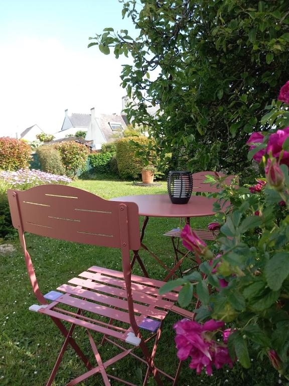 un banc en bois assis à côté d'une table avec des fleurs dans l'établissement Maison 3 étoiles proche des plages, à Pont-lʼAbbé