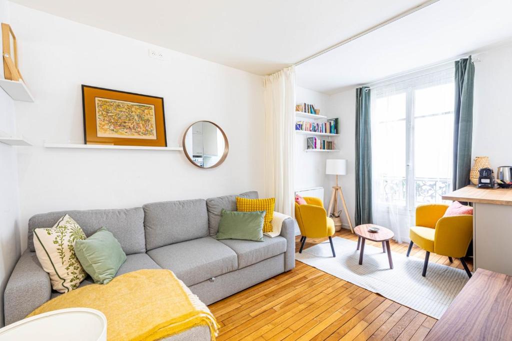 - un salon avec un canapé gris et des fauteuils jaunes dans l'établissement GuestReady - Peaceful Retreat in Batignolles, à Paris