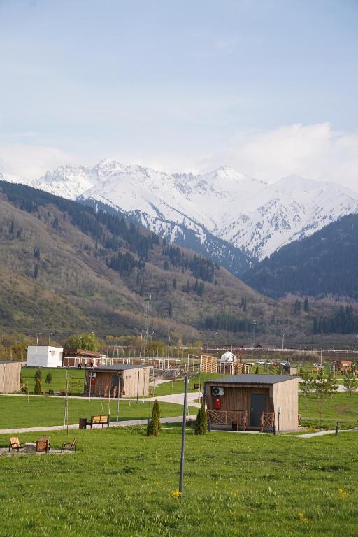 a farm with snow covered mountains in the background at Eco-hotel AQBULAQ in Kaynazarka