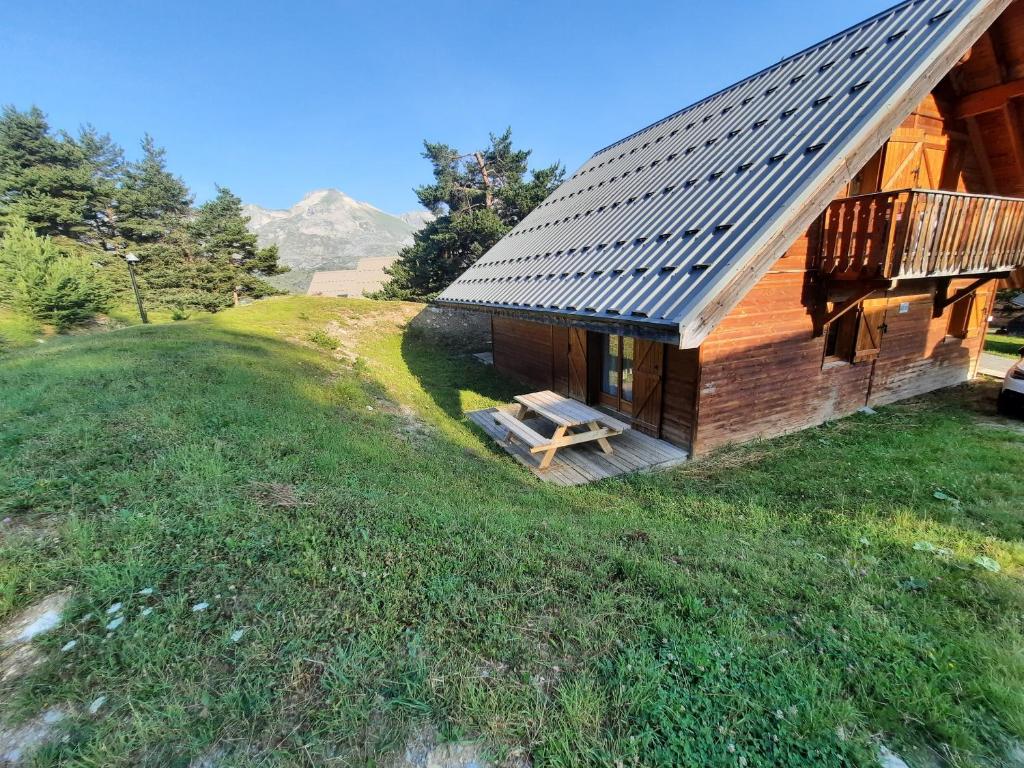 a log cabin with a deck on a grassy hill at Chalet Bastilor in La Joue du Loup