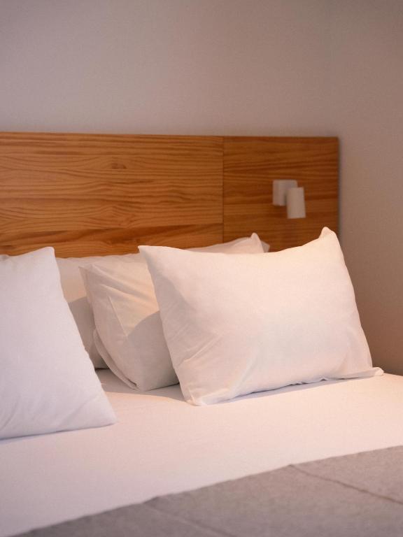 a bed with white pillows and a wooden headboard at HOTEL ALOVE in San José