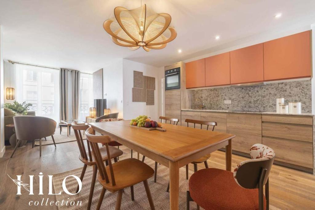 une cuisine et une salle à manger avec une table et des chaises en bois dans l'établissement HILO Suite Paris Balzac - 6 pers - 63m2, à Paris