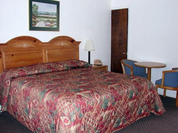 a hotel room with a bed and a table and chairs at Red Carpet Inn & Suites Morgantown in Morgantown