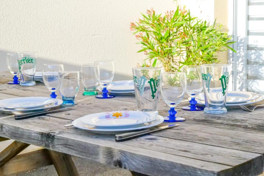 une table en bois avec des assiettes et des verres dans l'établissement Maison de vacances - quartier calme - 6 personnes, à Les Sables-dʼOlonne
