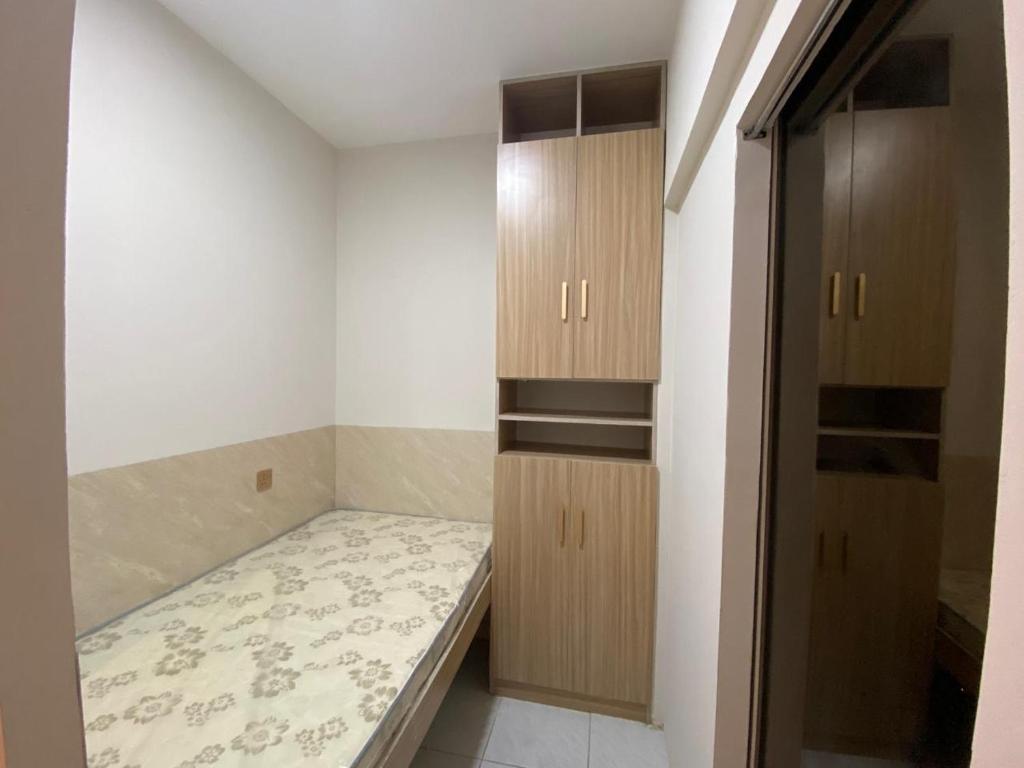Kleines Zimmer mit einem Bett und Holzschränken in der Unterkunft Garden Residence in Dubai