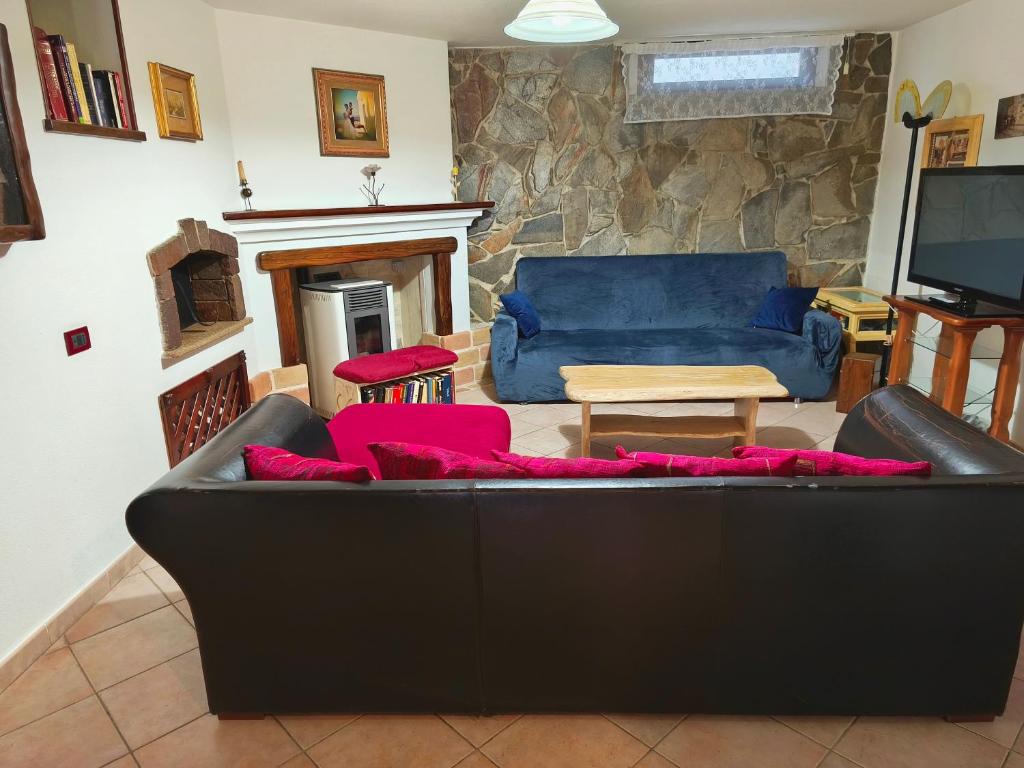 a living room with a black couch and a tv at Casa Magnolia in Galtellì