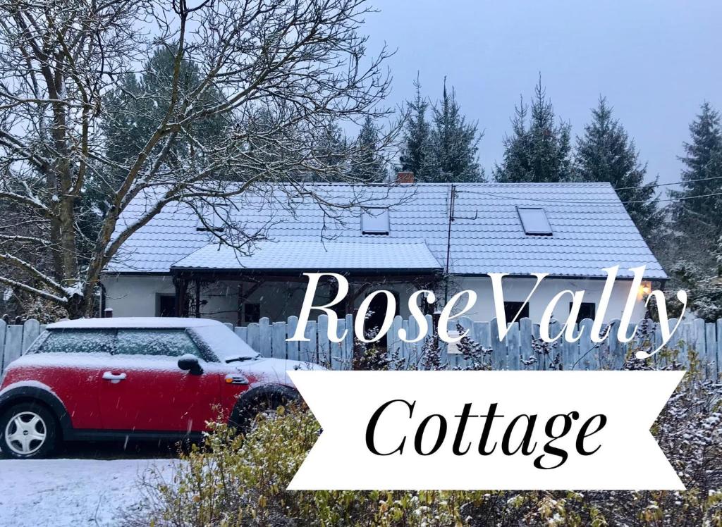 ein rotes Auto, das vor einem Haus im Schnee geparkt ist in der Unterkunft Rose-Vally Cottage in Borský Svätý Jur