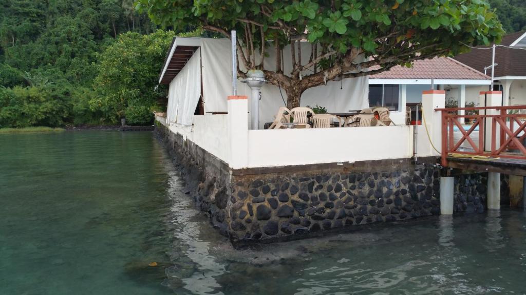 a house with a table and chairs next to the water at Pension de famille HITI MOANA VILLA in Papara