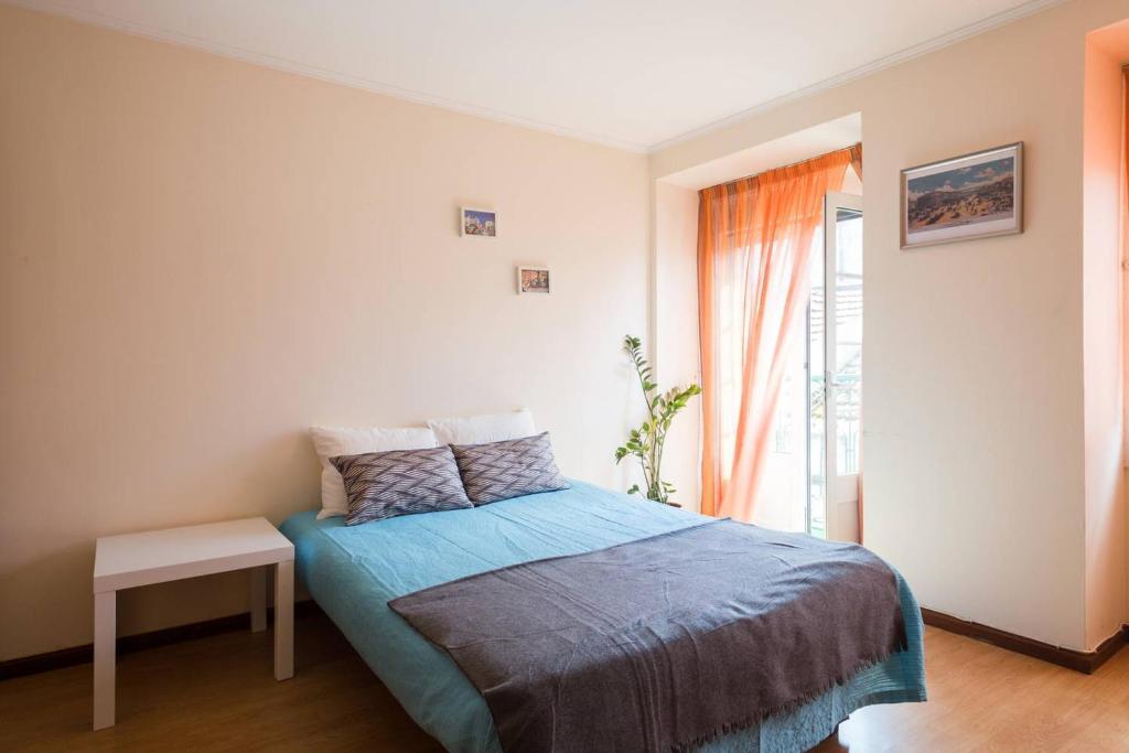 リスボンにあるCasa Nossaのベッドルーム1室(青い毛布、窓付)