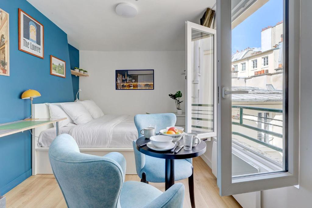 une petite pièce avec un lit, une table et des chaises dans l'établissement Le Reve Parisien a Montorgueil, à Paris