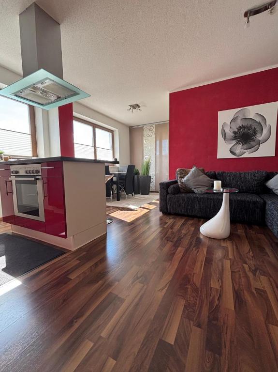 a living room with a red accent wall and a kitchen at Apart Spieljochbahn in Fügenberg