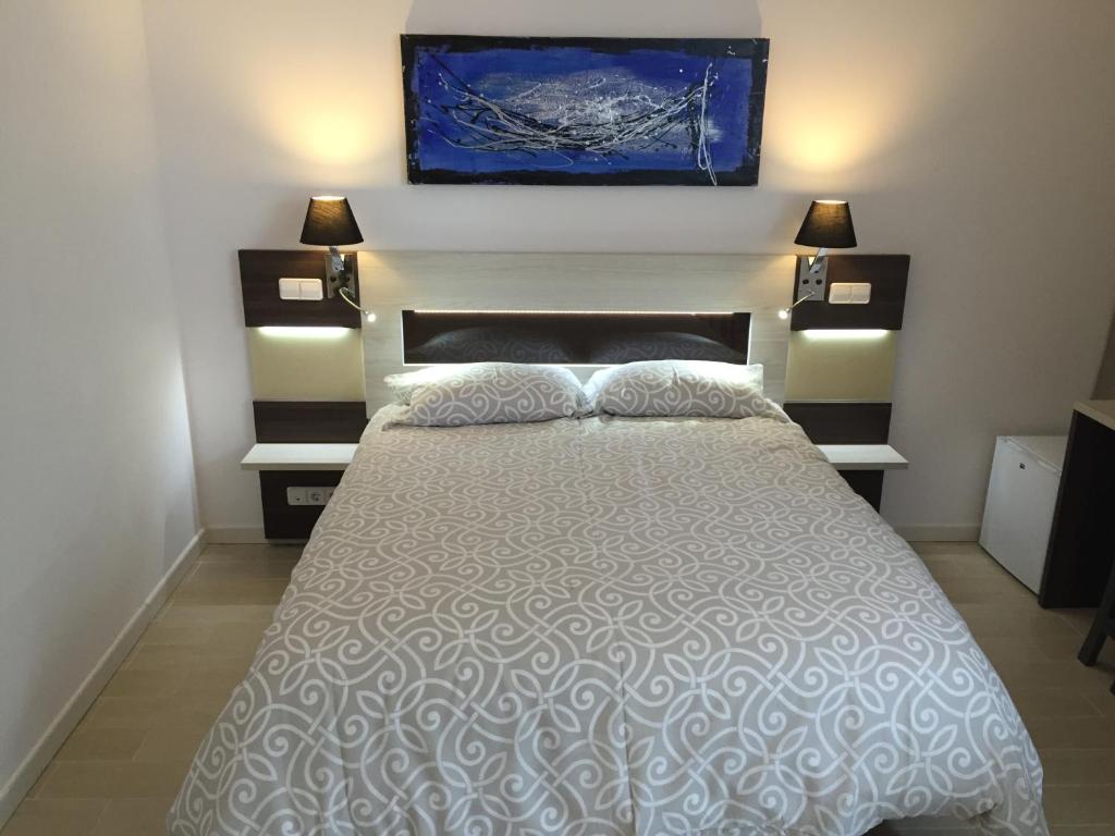 ein Schlafzimmer mit einem Bett mit zwei Lampen und einem Gemälde an der Wand in der Unterkunft H Skyline in Alcorcón