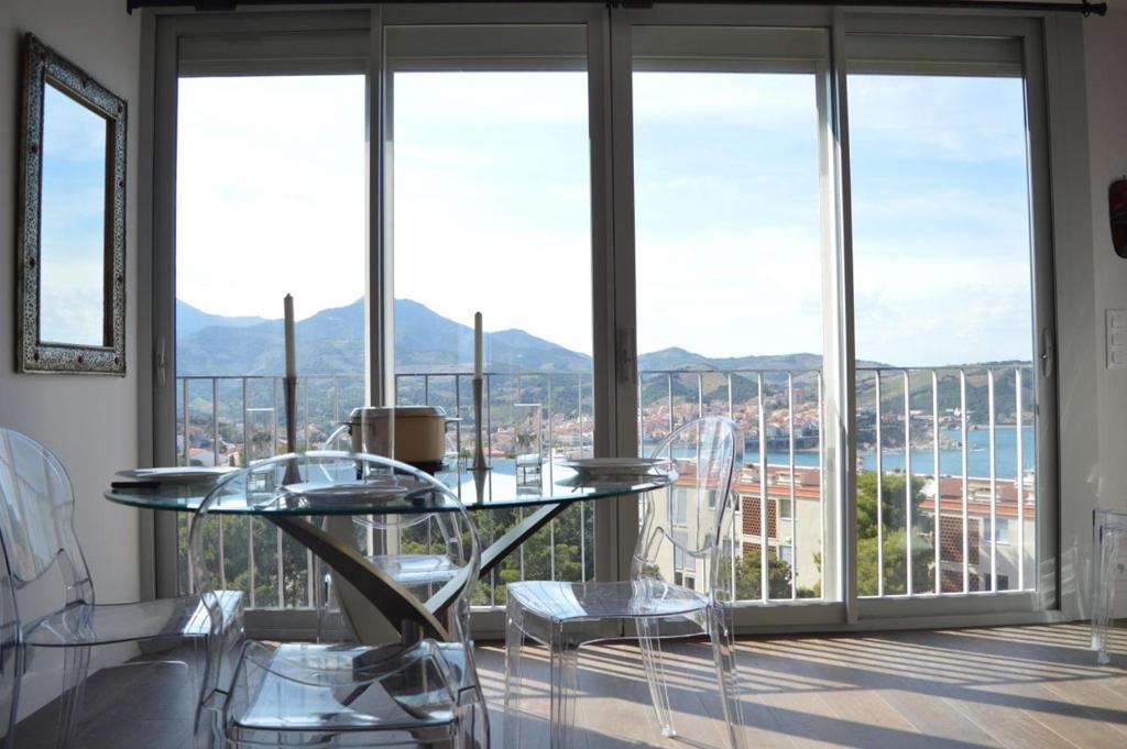 une table et des chaises en verre dans une pièce avec fenêtres dans l'établissement Appart 2 pièces 4 couchages BANYULS SUR MER BN100-D142, à Banyuls-sur-Mer