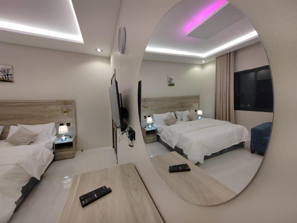 a hotel room with two beds and a mirror at استوديو رائع بجلسة ودخول ذاتي in Quai