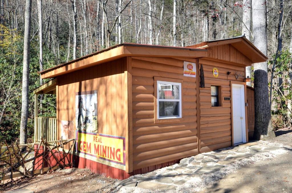 - un petit bâtiment en bois avec un panneau devant dans l'établissement Log Cabin Getaway in the Mountains for Two near Maggie Valley, North Carolina, à Cherokee