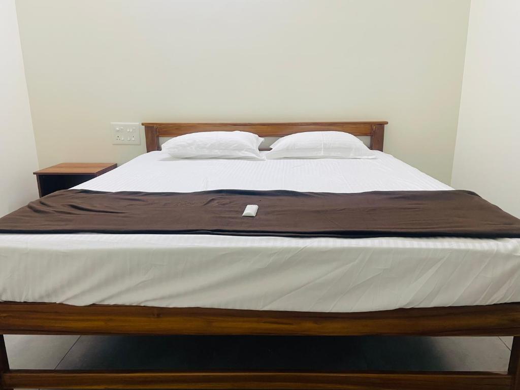 a bed with a wooden frame and white sheets at Yogi Ram Guest House in Tiruvannāmalai