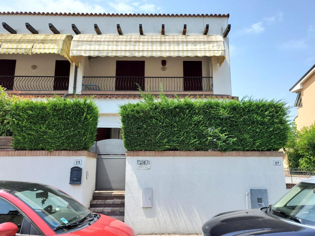 a white house with a balcony and parked cars at Villetta Imola in Lido degli Estensi