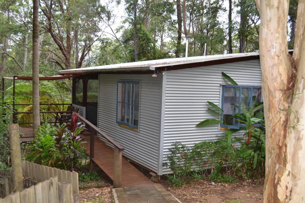 a small white house with a porch and a fence at Palmwoods Eco Escape in Palmwoods