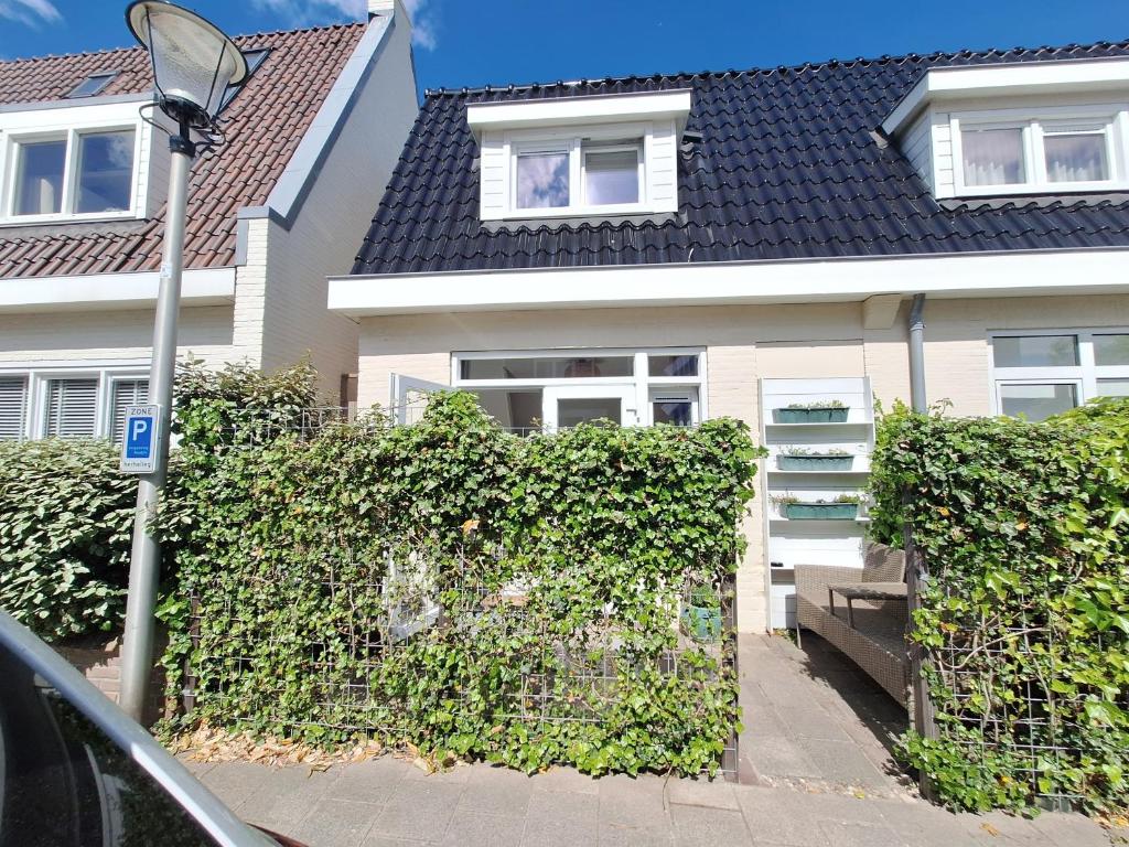 a house with a hedge in front of a building at Huisje Louis in Zandvoort