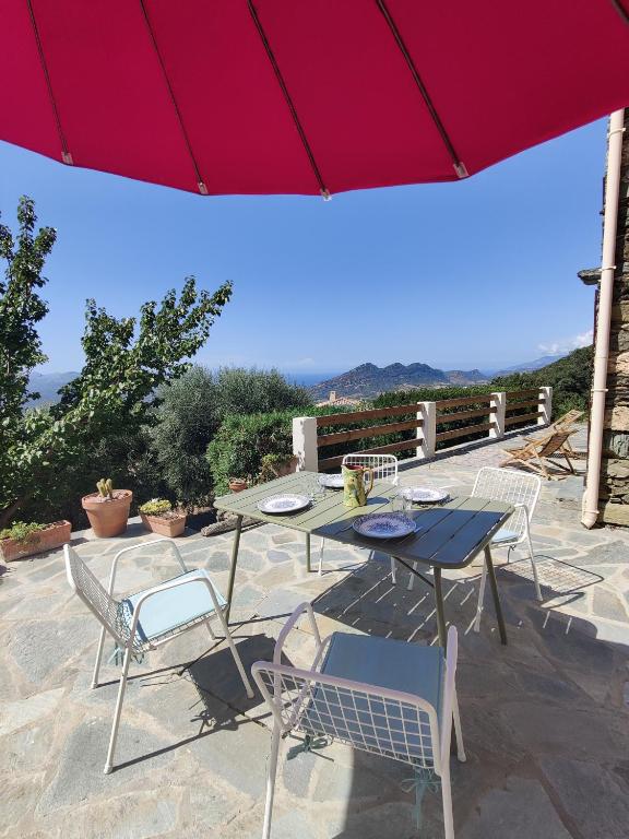 un patio avec une table, des chaises et un parasol dans l'établissement Casa Orsu vue panoramique, à Poggio-dʼOletta