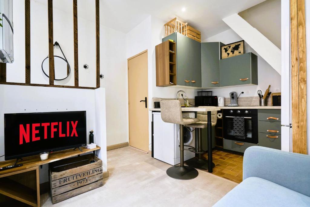 une cuisine avec des armoires vertes et une télévision dans une pièce dans l'établissement Maison du Vieux lille - moderne et authentique, à Lille