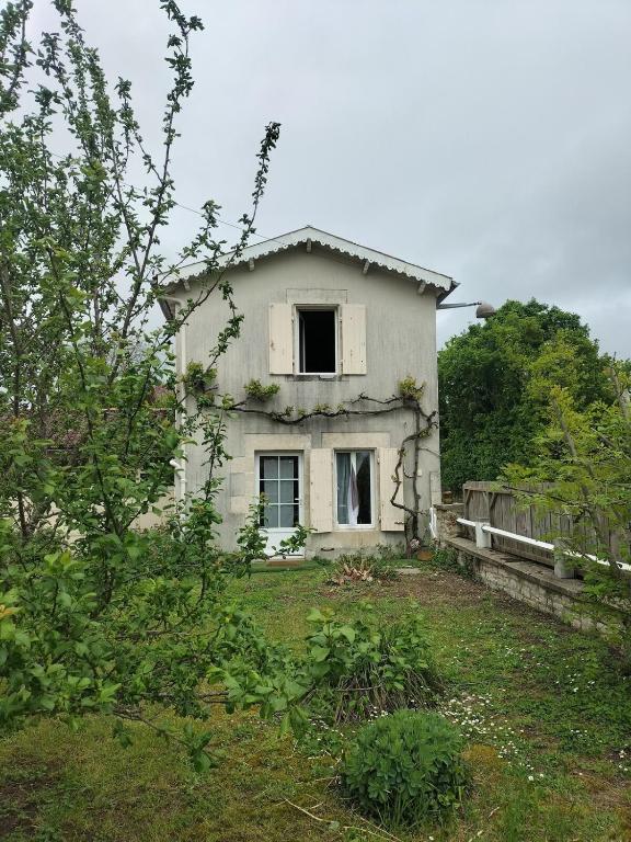 une vieille maison blanche avec une fenêtre dans une cour dans l'établissement Studio in all its simplicity, à Le Bourdet