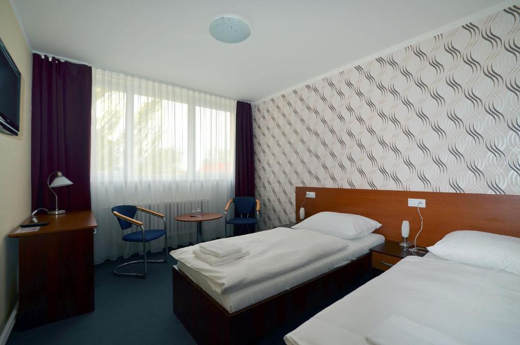 a hotel room with two beds and a table and chairs at Arkada Hotel in Bučovice