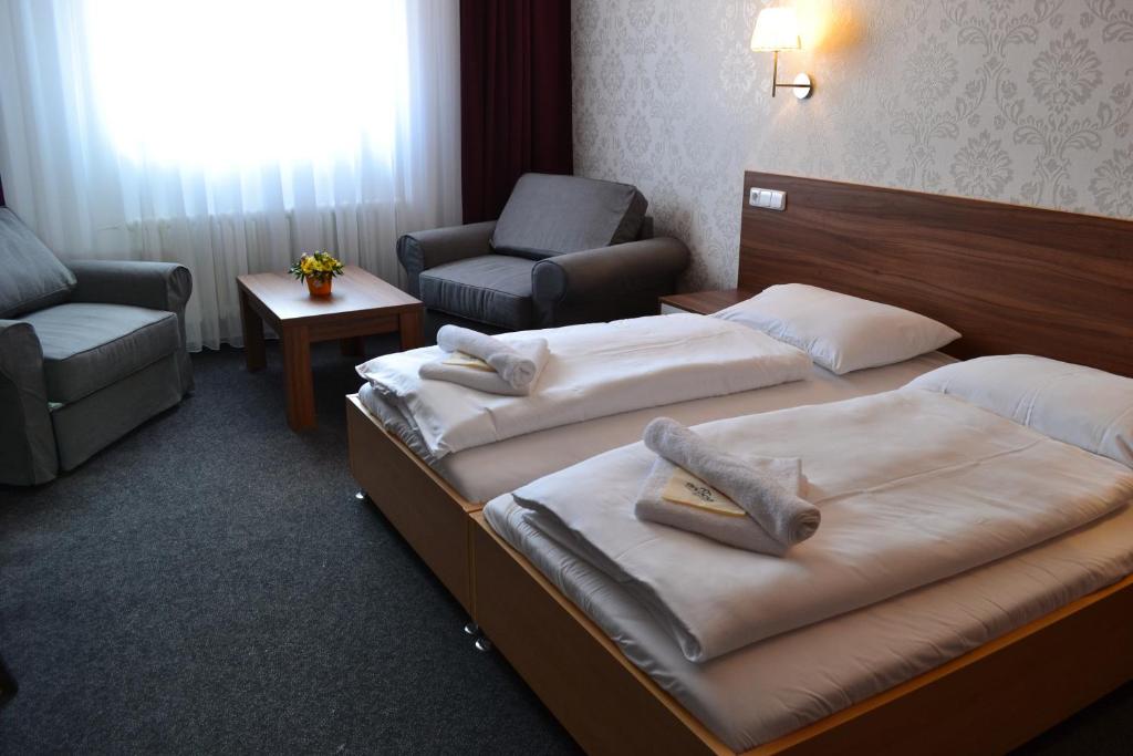 a hotel room with two beds and a chair at Arkada Hotel in Bučovice