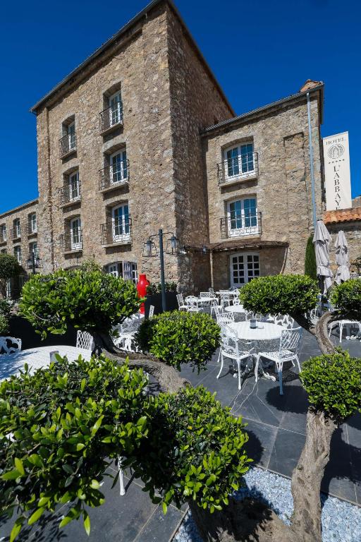 a building with tables and chairs in front of it at Hôtel L'Abbaye in Calvi