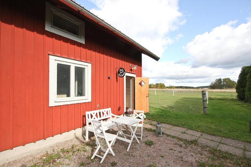 ein rotes Gebäude mit einem Tisch und Stühlen außerhalb des Gebäudes in der Unterkunft Broby Bed & Breakfast in Nyköping