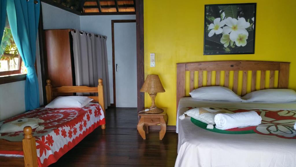 two beds in a room with yellow walls at Pension de famille HITI MOANA VILLA in Papara