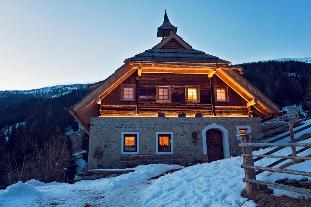 una cabaña de madera en la nieve junto a una valla en Sandrisser-Hütte, en Innerkrems