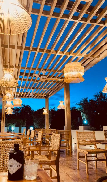 un patio con sedie, tavoli e lampadari a braccio di Zante Pantheon Hotel a Tsilivi
