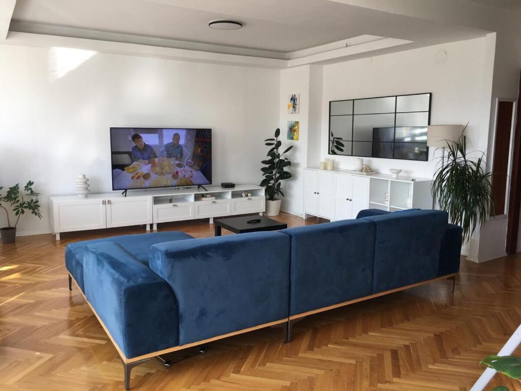 ein Wohnzimmer mit einer blauen Couch und einem Fernseher in der Unterkunft Dijuto Apartment in Skopje