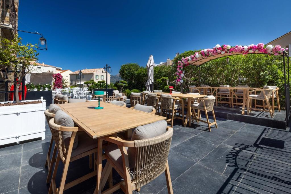 a patio with tables and chairs and an arbor at Hôtel L'Abbaye in Calvi